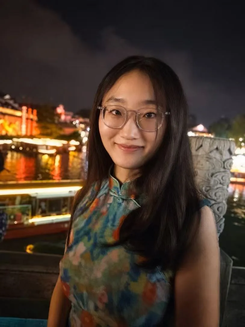 女性站在夜晚的水岸灯光前